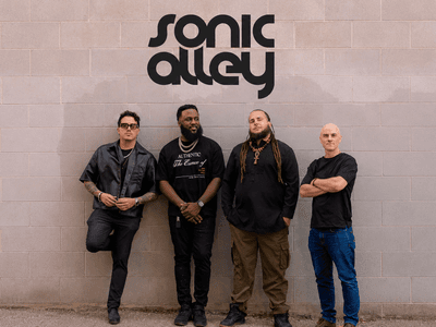 Sonic Alley band members standing beneath the Sonic Alley logo against a brick wall.