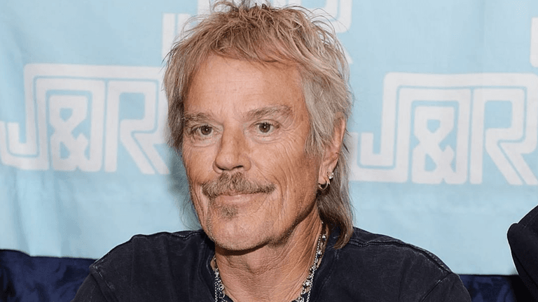 A man with light hair and a mustache smiles at a signing event
