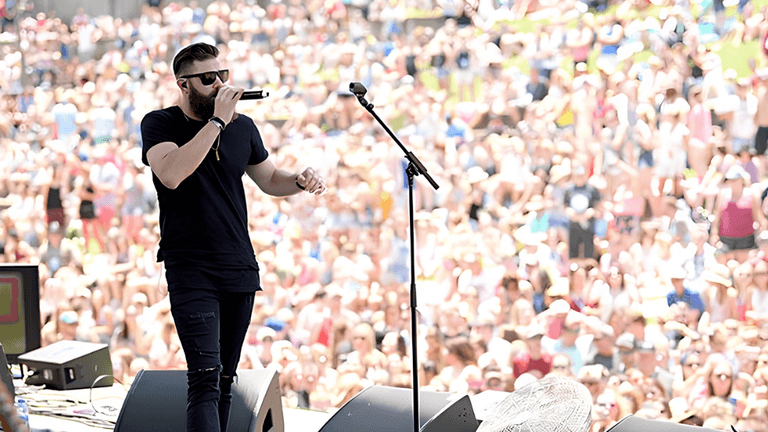 A singer performing on stage in front of a large crowd during a festival.