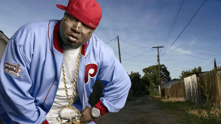 A man in a red cap and blue jacket poses in an outdoor setting.