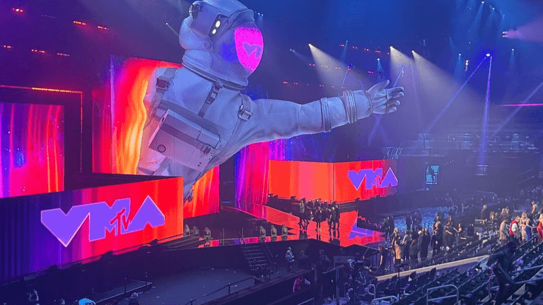 Stage setup for an event with colorful screens and a giant astronaut figure