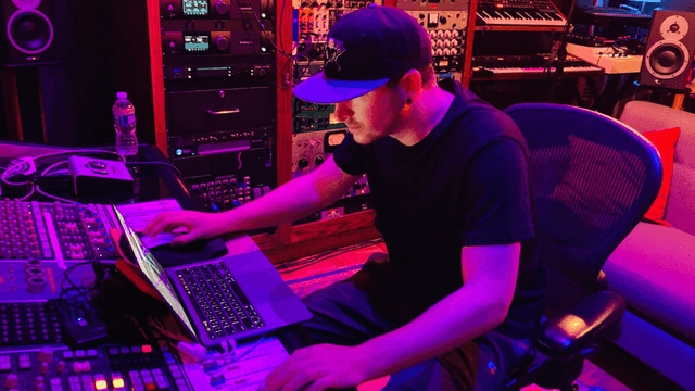 Maks Gabriel working at a recording studio mixing music on a laptop and audio production equipment.