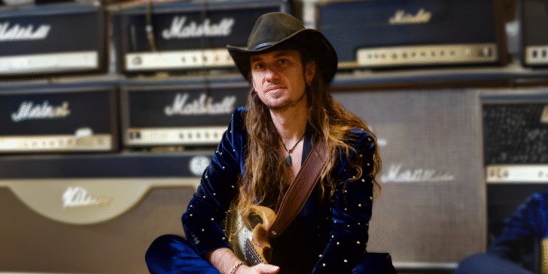 Ulrich Ellison, founder of Total Guitar Transformation (TGT), sitting with a guitar in front of Marshall amplifiers, embodying his passion for music and teaching. TGT's innovative, personalized approach helps adult learners over 40 rediscover their love for guitar through practical, creative methods inspired by legendary musicians like Jimi Hendrix
