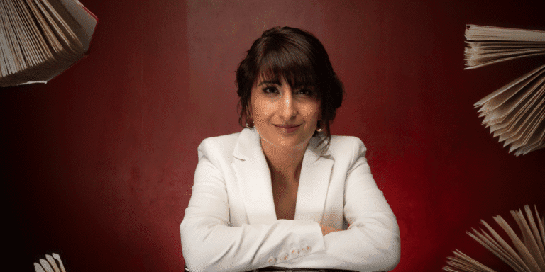 Kully Bath in white blazer with floating books, smiling confidently against a deep red background.