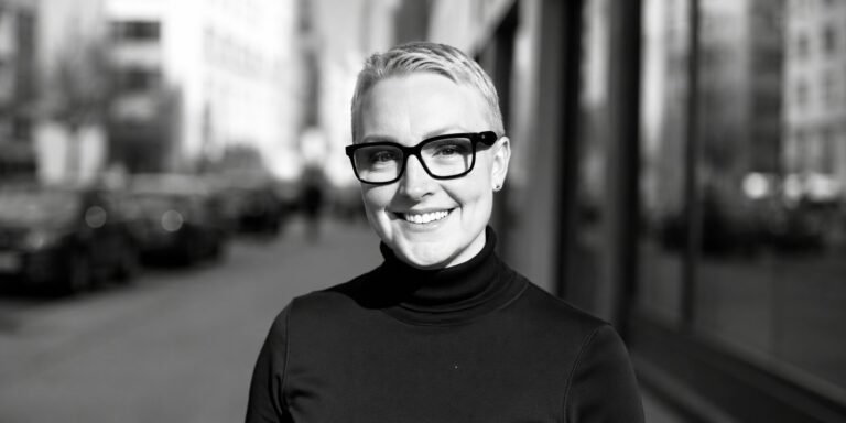 Jeannette’s Voice Studio Brings Personalized Voice Coaching to Performers and Professionals Jeannette Papadakis smiling outdoors in a black turtleneck and glasses.