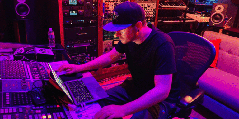 Maks Gabriel Builds Songs With Lasting Value Maks Gabriel working at a recording studio mixing music on a laptop and audio production equipment.