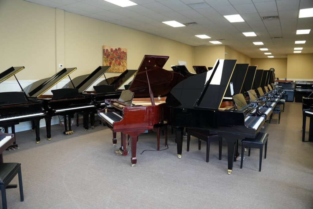 Showroom filled with grand and upright pianos arranged in rows for comparison.